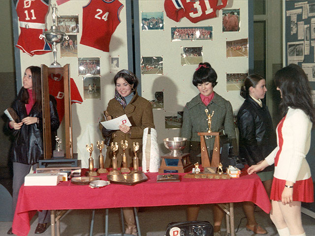 Cinq jeunes filles qui admirent trophées, photographies et autres articles aux couleurs des équipes du Cégep de Trois-Rivières