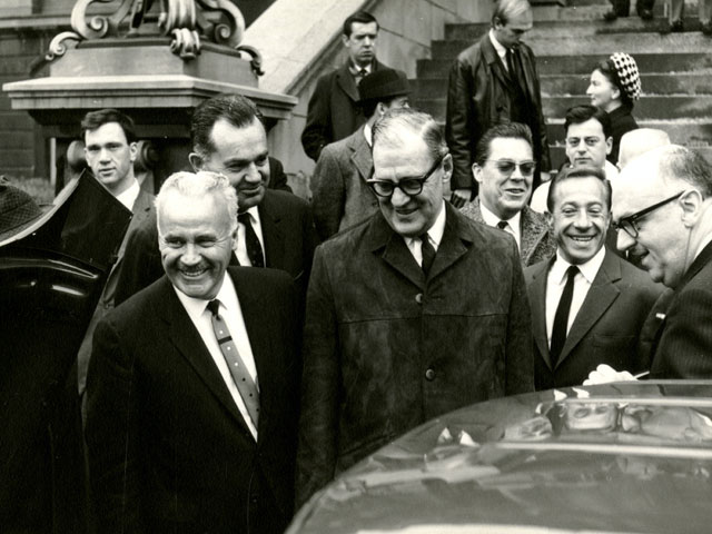 The photo features Gérard Filion in the company of Montréal Mayor Jean Drapeau and representatives of the French companies during a negotiation meeting